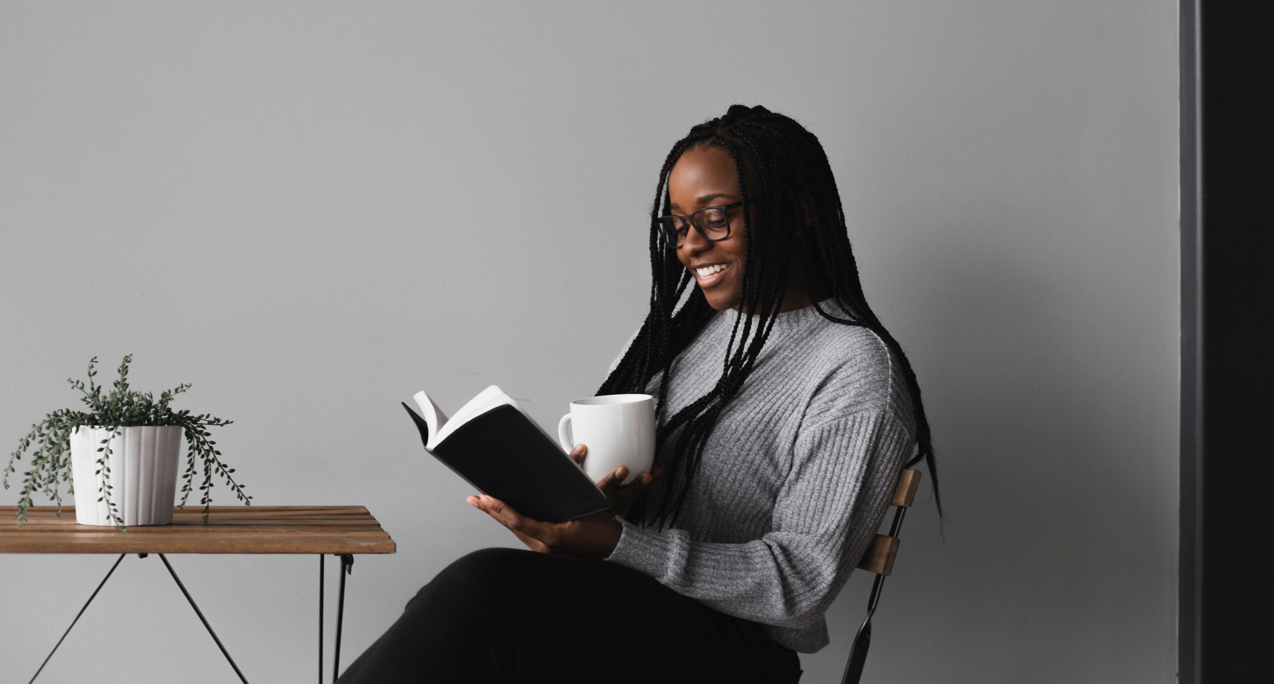 woman smiling while reading and drinking a coffee