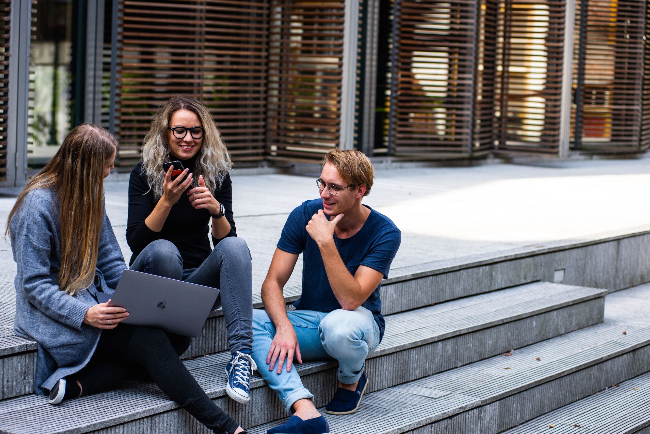 three people sitting on steps talking with each other