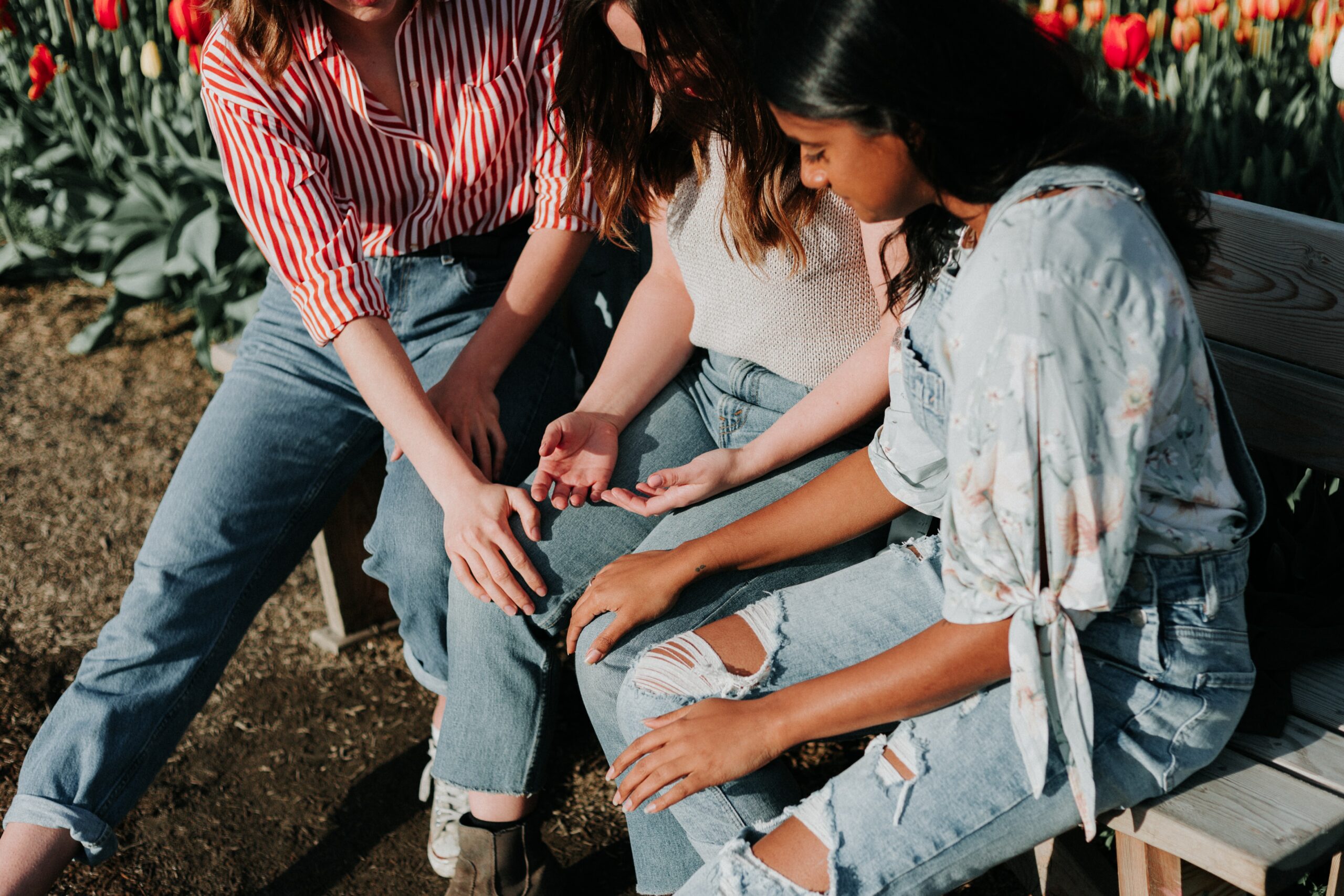 three people sitting on a bench talking