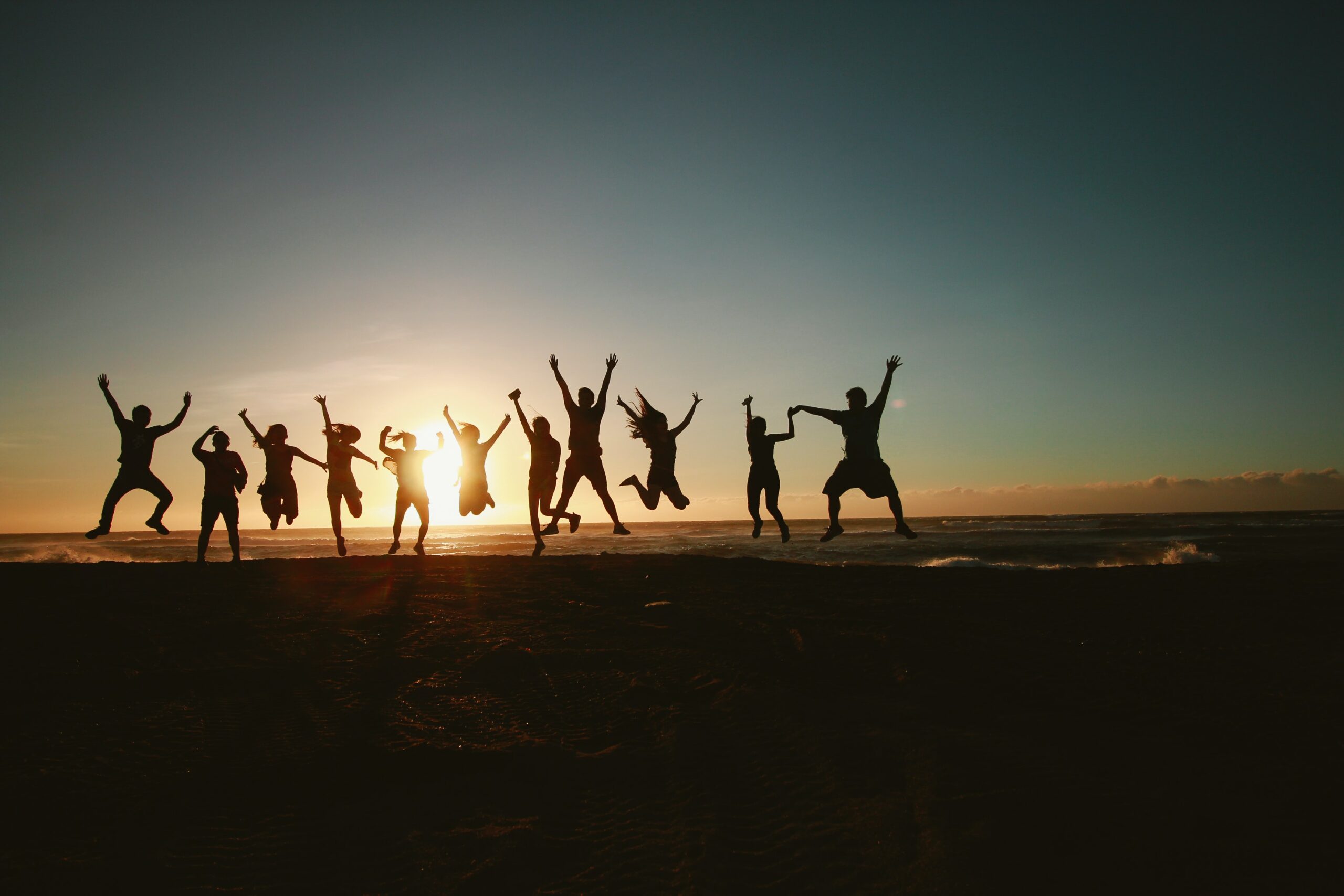 picture of people jumping on a beach as sunset