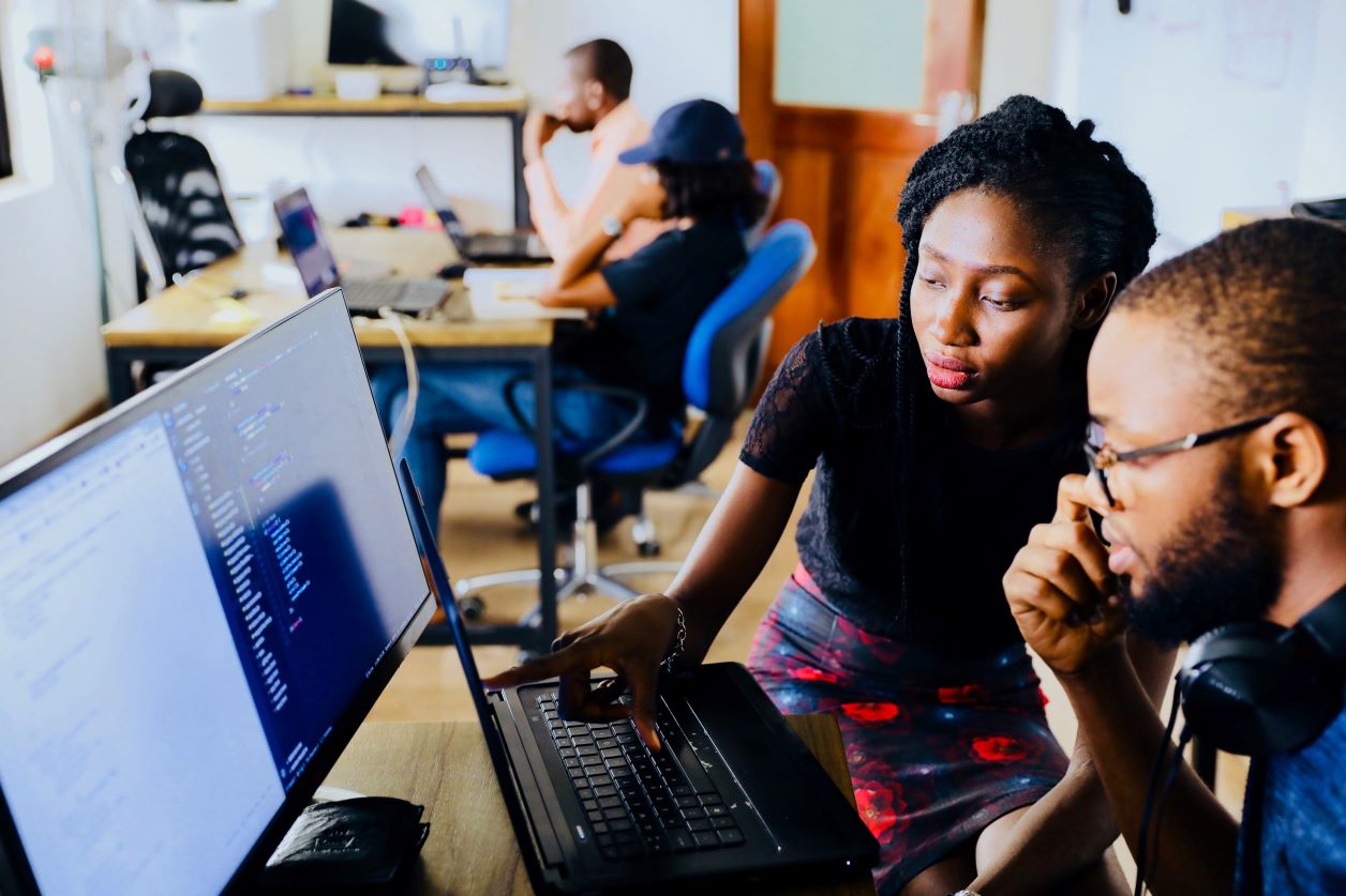 two people talking and looking at a computer