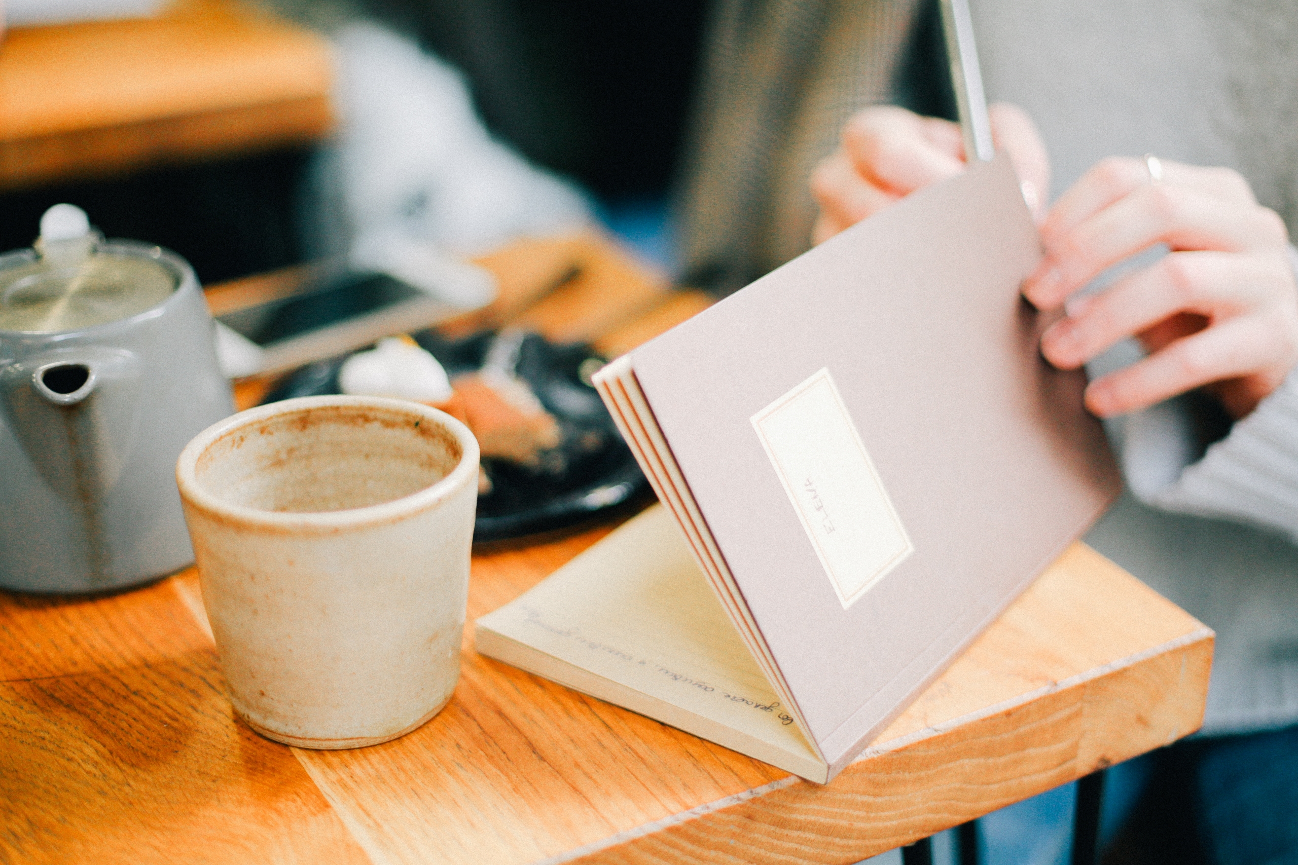 woman working in a cafe, with a coffee and notebook