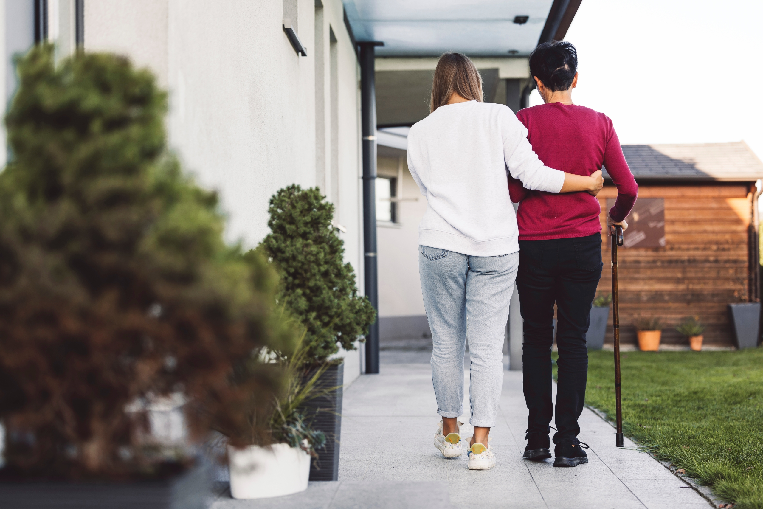 Carer helping someone walk in palliative care