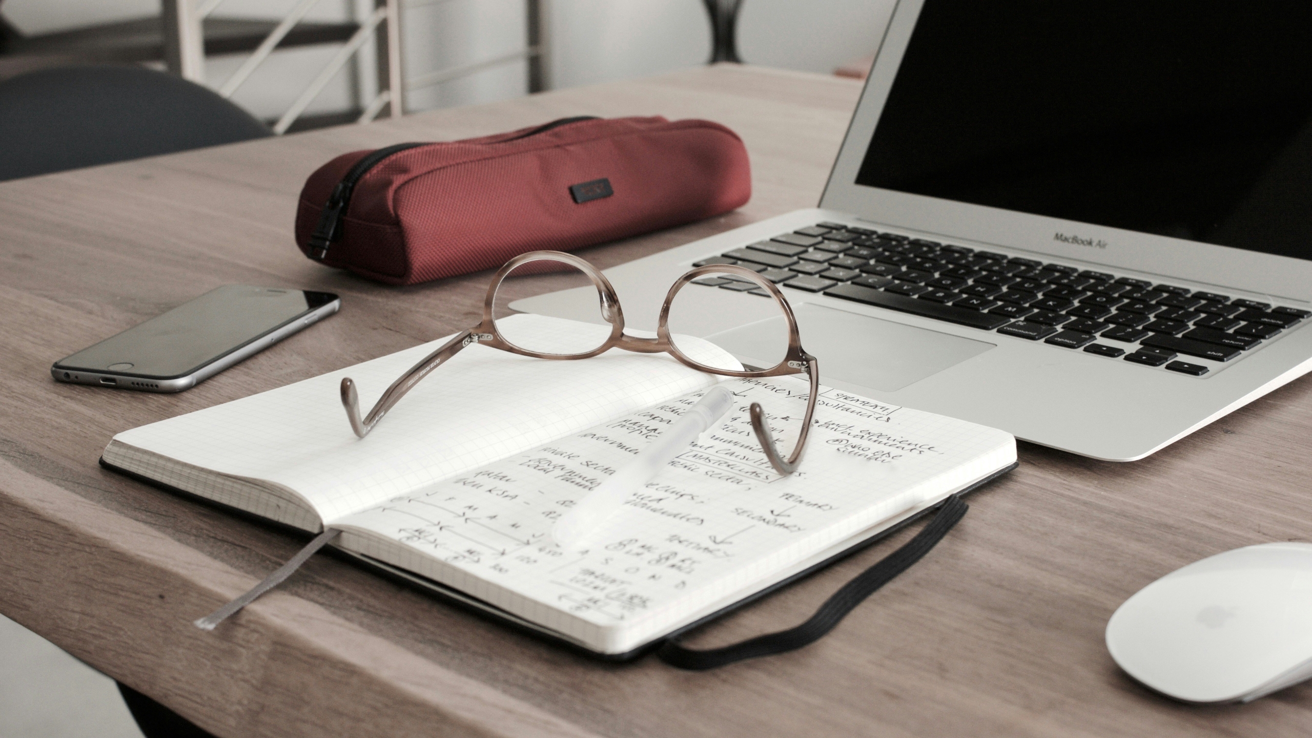 laptop and notebook with glasses sitting on top